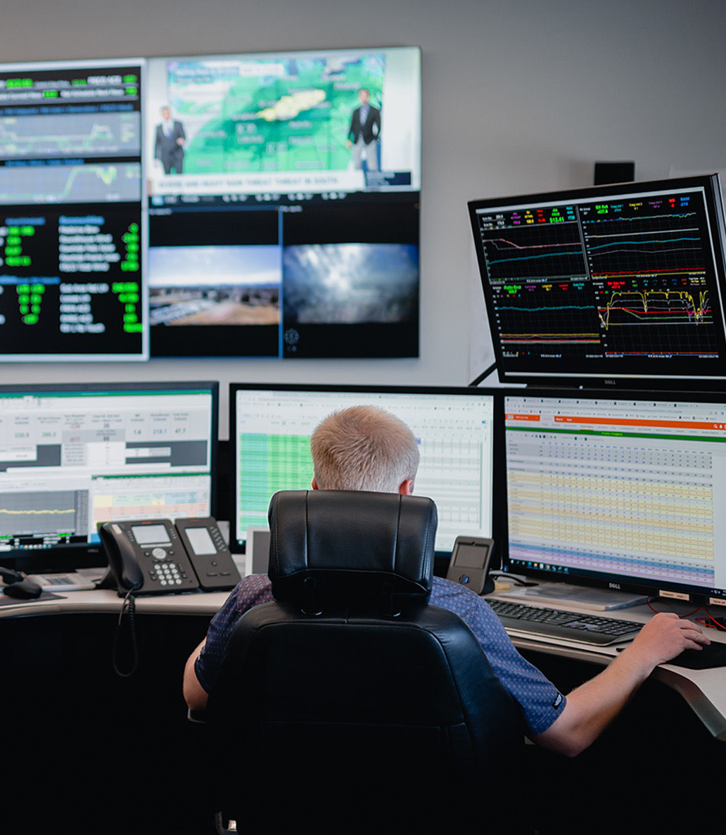 Back view of a man sitting at a desk looking at monitors